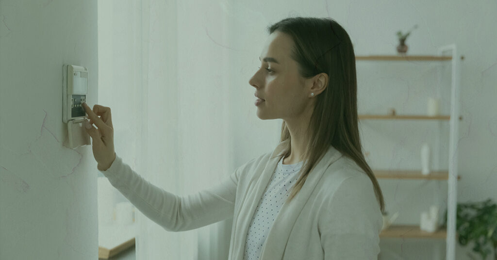 woman setting heat temperature on home thermostat